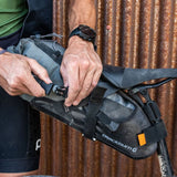Dry bag being secured by buckle in the Blackburn Outpost Elite Universal Seat Bikepacking Pack